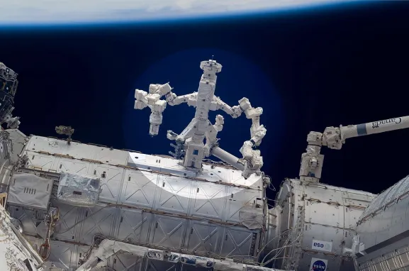 Photo du robot Dextre muni de deux bras articulés. Le robot est attaché à la Station spatiale internationale.